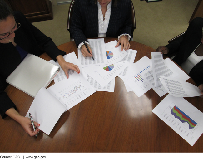 People with documents around a conference table