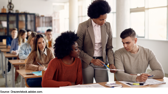 A teacher helping adult students in a classroom