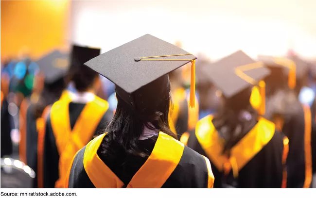 Stock image showing college graduates in cap and gown with gold sashes.